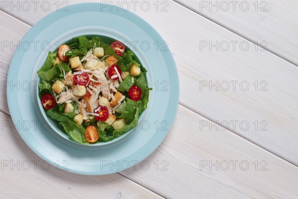 Classic Caesar salad, with cherry and croutons, top view, on a white table, horizontal, no people
