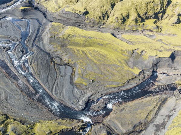 River along road F232 Öldufellsleid, slopes of Mt. Öldufell, moss-covered hill in black lava sand,