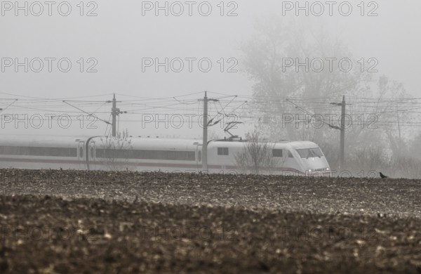 A Deutsche Bahn ICE train runs in foggy autumn weather on a railway line near Neugarten, 06.11
