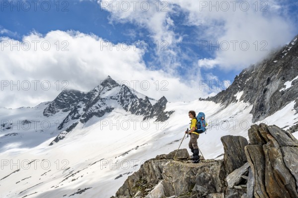 Mountaineer on a rock between snow, descent from the summit of Schönbichler Horn, view of