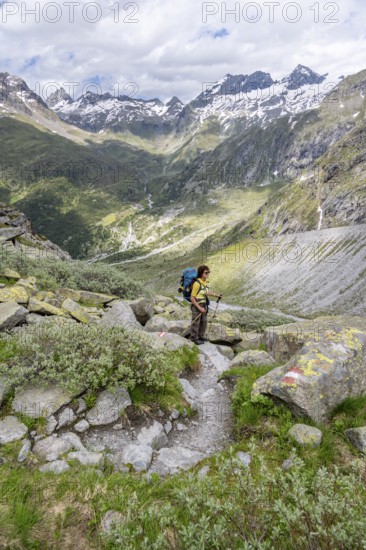 Mountaineer on a hiking trail in front of a picturesque mountain landscape, rocky mountain peaks