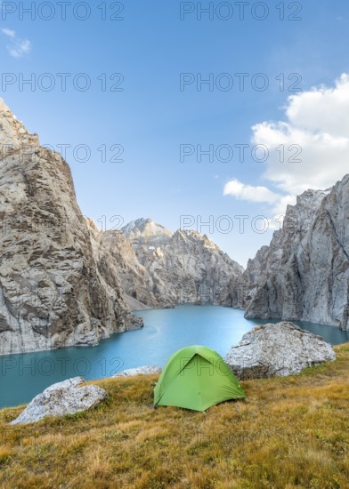 Green tent at the turquoise mountain lake Kol Suu with rocky steep mountains, Kol Suu Lake, Sary