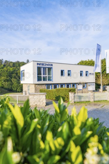 Modern information centre building with large glass windows and fences, surrounded by green nature,