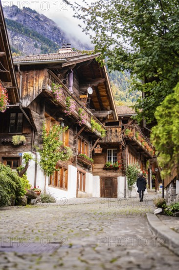 Person walking through a picturesque old street with half-timbered houses in autumn, Lake Brienz,