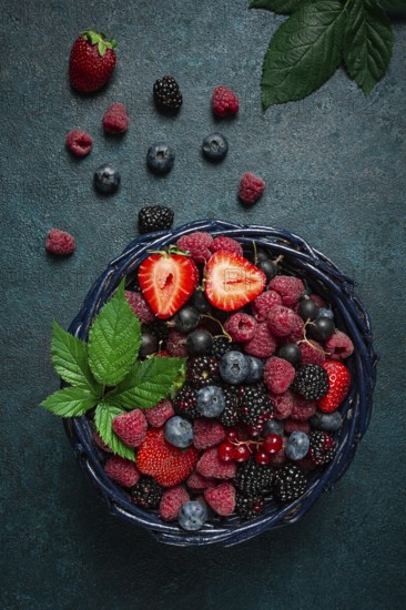 Mix of fresh berries, in a basket, on a wooden gray table, no people, top view