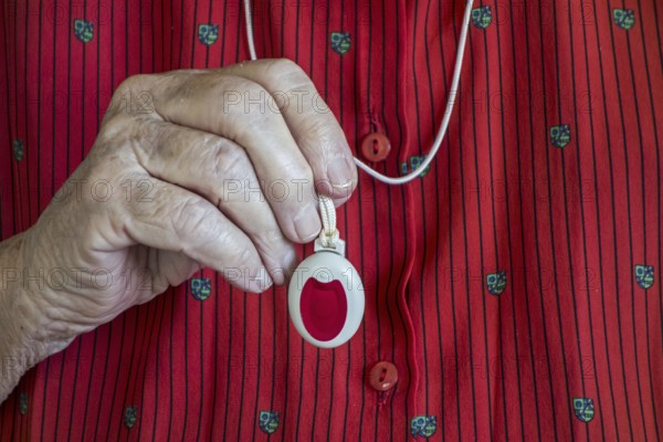 Close up of hand holding life-saving personal alarm for the elderly and disabled people showing