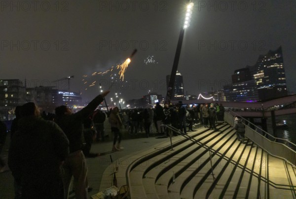 Person launches firework rocket from his hand, New Year's Eve 2025 on the Elbe promenade in