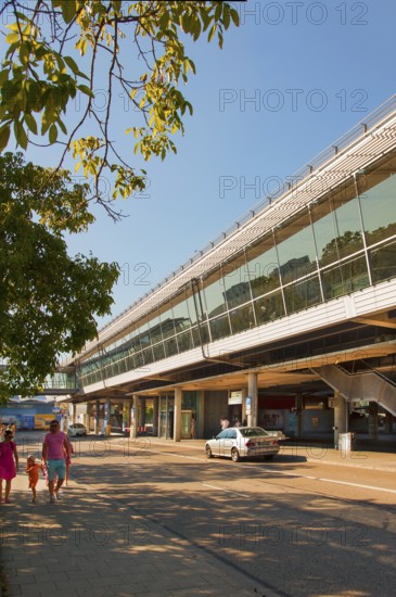 Modern railway station with glass facade, surrounded by trees, on a sunny day, Fröttmaning