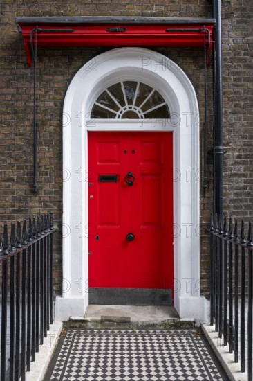Red entrance door in a brick building with a cast-iron fence, Charles Dickens Museum, 48-49 Doughty