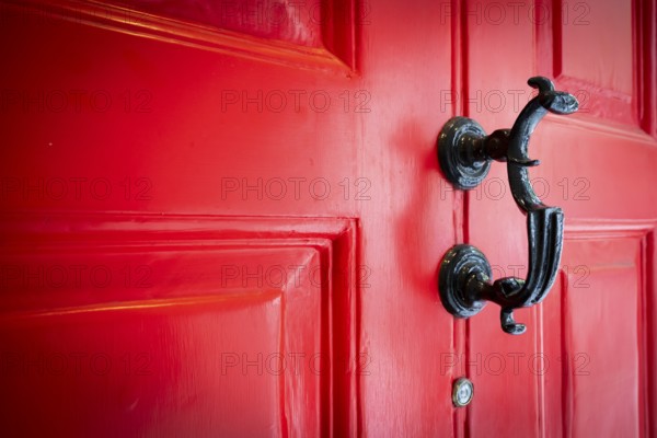 Close-up of a black door knocker on a red door, entrance to the Charles Dickens Museum, 48-49