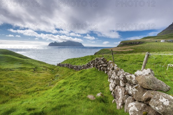 View of the island of Mykines, old stone wall, Gásadalur village, Vágar, Faroe Islands, Denmark,