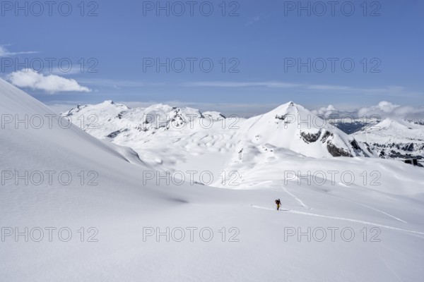 Lone ski tourer in mountain landscape with snow, summit Mittaghorn and Wildhorn, ascent to