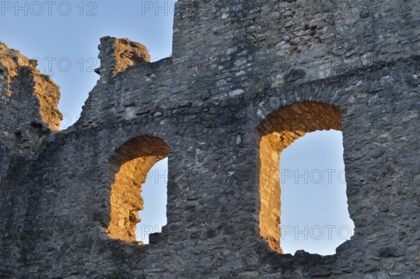Old stone ruins with two window openings, illuminated by the warm light of the golden hour,