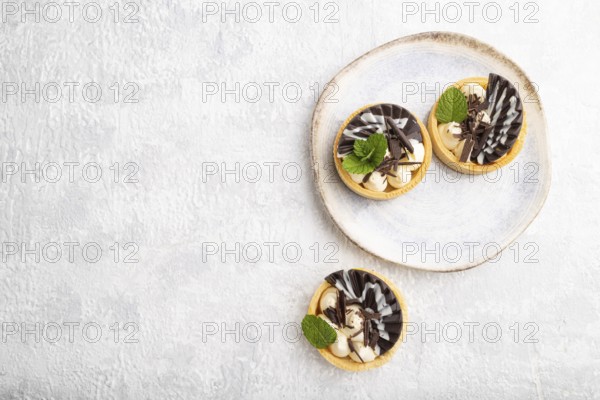 Sweet tartlets with chocolate and cheese cream on a gray concrete background. top view, flat lay,