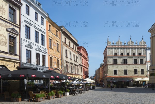 Town square with historic facades and street cafés under a blue sky, Chociszewska tenement house,