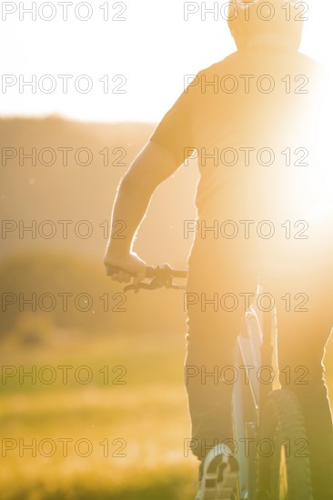Silhouette of a cyclist in strong sunlight on a dirt track, e-bike, forest bike, Calw, district of