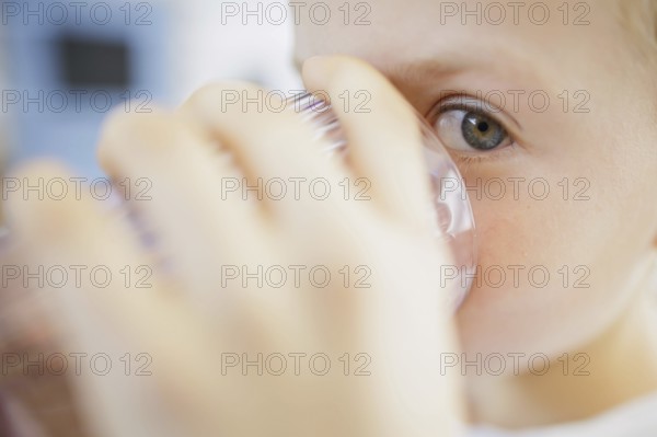 Symbolic photo on the subject of drinking water in high temperatures. A boy drinks a glass of water