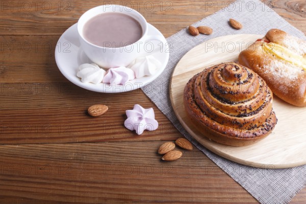 A cup of hot chocolate and buns on brown wooden background. close up, copy space