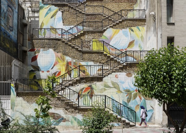 Passers-by walk up a staircase painted with roses in Tehran. The city of Tehran is changing the
