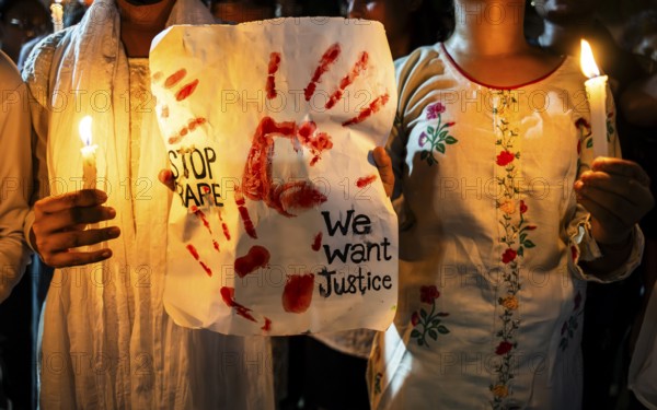 Students holds candle and shout slogans as they participate in a protest against the rape and