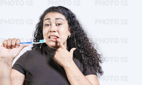 Young woman with gingivitis holding toothbrush isolated. Girl suffering from gum pain holding