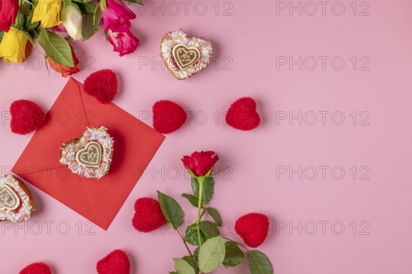 Valentine's Day composition with roses, hearts and envelope, heart-shaped cupcakes, on a pink