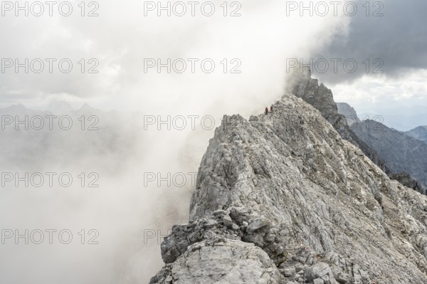 Clouds move around narrow rocky mountain ridge with mountaineers, Watzmann crossing to Watzmann