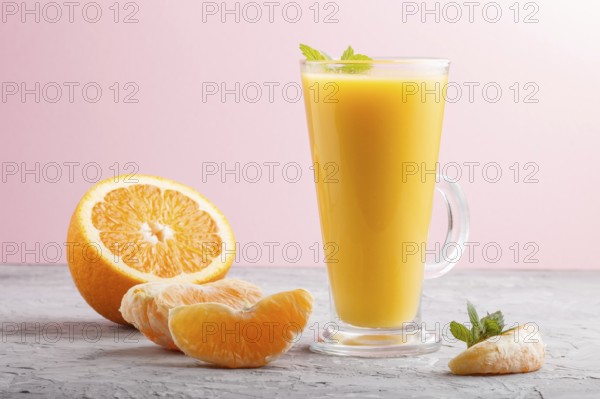 Glass of orange juice on a gray and pink background. Morninig, spring, healthy drink concept. Side