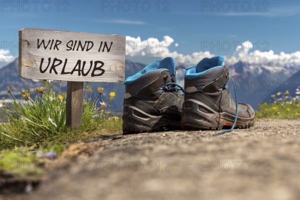 Symbolic image of company holidays/summer holidays: Hiking boots in front of an alpine backdrop and