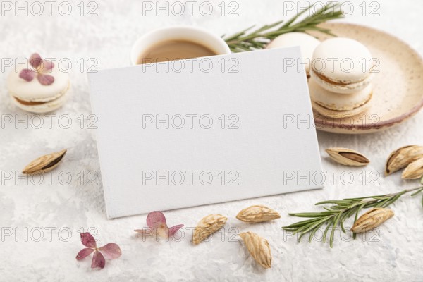 White business card mockup with cup of coffee, almonds and macaroons on gray concrete background.