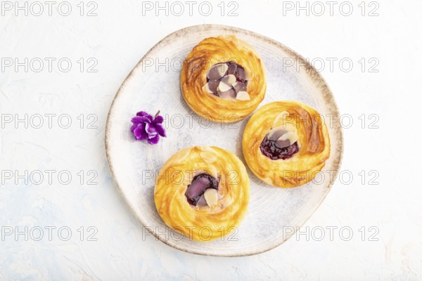 Small cheesecakes with jam and almonds with cup of coffee on a white concrete background. top view,