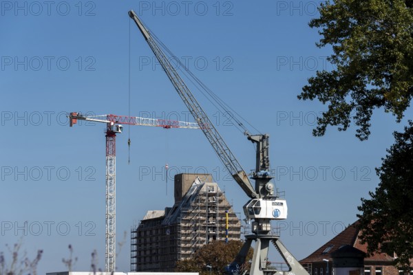 Old silo building, warehouse, in front of it construction crane and harbour crane, Magdeburg Port