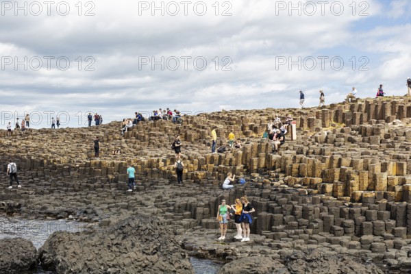 Groups of people on an impressive rock formation on the coast, Giant Causeway