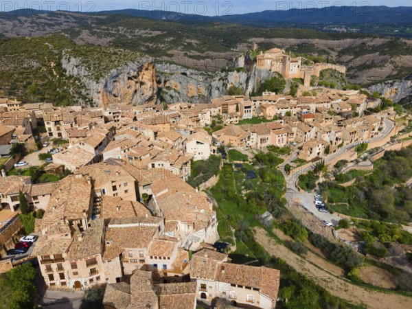 A picturesque medieval village with tiled roofs in a mountainous landscape, aerial view, collegiate