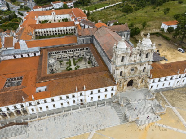 Historic monastery with red roof and courtyard, surrounded by landscape, aerial view, Mosteiro de