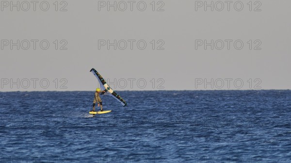 Wingfoiller, single kitesurfer over the waves of the calm sea, windsurfer, Meltemi windsurfing
