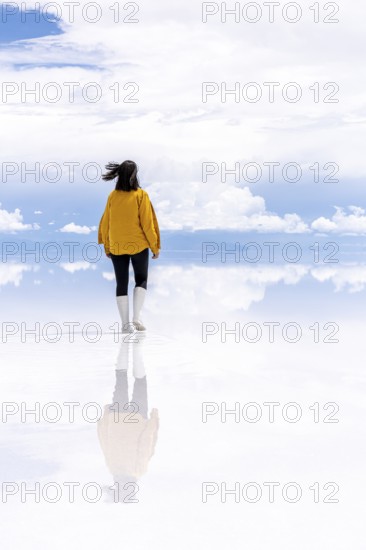 Young woman walks across the Uyuni salt lake, Salar de Uyuni, Uyuni, Bolivia, South America