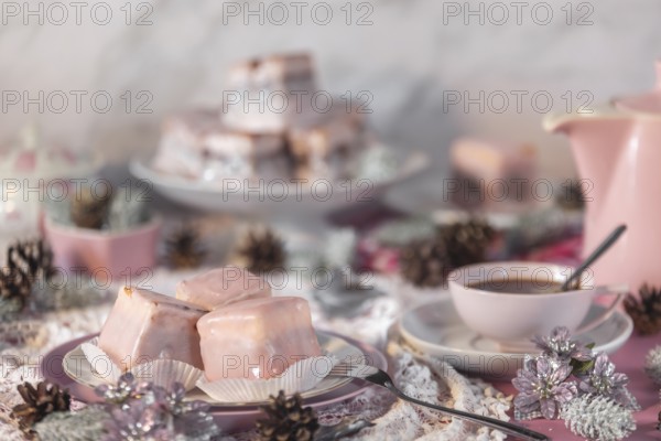 Pink glazed cakes, punch doughnuts surrounded by winter decorations, coffee pot and cup of coffee