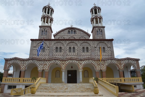 Imposing church with two towers and flags against a cloudy sky, Church of Agios Georgios, Nea