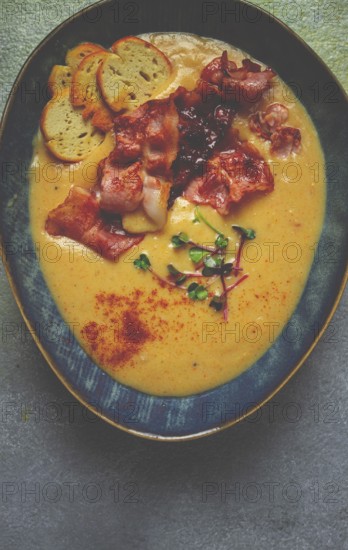Pumpkin cream soup, curry, fried bacon, bruschetta chips, micro-greens, top view, no people
