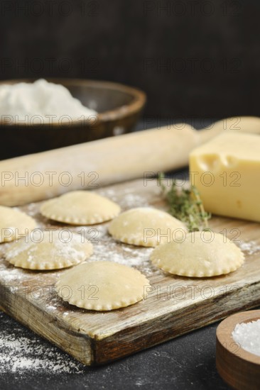 Fresh pasta is being prepared on a wooden board with flour and butter visible, alongside a rolling