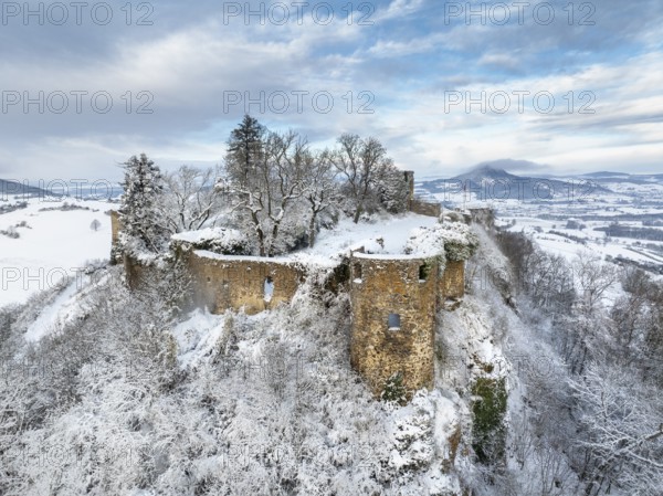 Aerial view of the snow-covered Hegau volcano Mägdeberg with remains of a castle wall on a cold