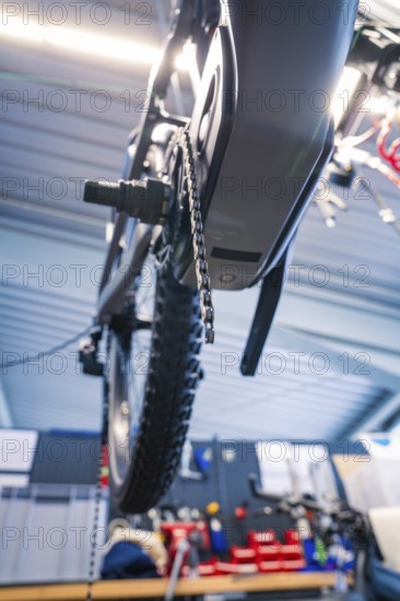 View of a bicycle chain and a wheel from below in a workshop, Waldbike Manufaktur, bicycle