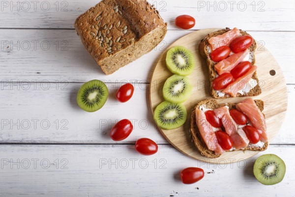 Smoked salmon sandwiches with butter and cherry tomatoes on white wooden background. top view, copy