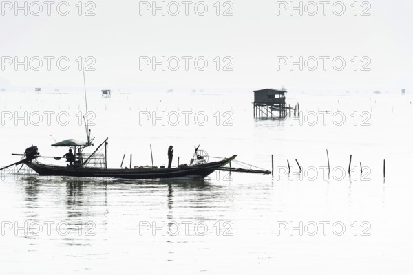 Traditional wooden huts of fishermen in the Gulf of Thailand in the morning haze, fishing boat,