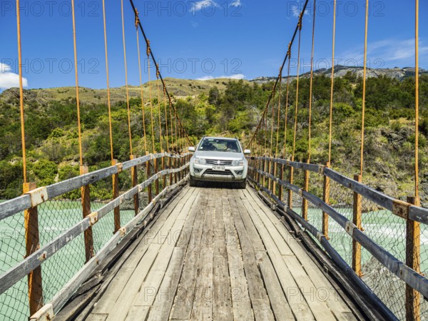 Small car (suv) crossing the river Rio Baker on an old suspension brige, bridge suitable for cars