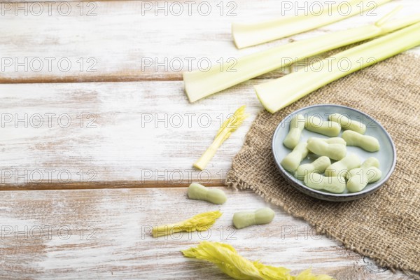 Jelly celery candies on white wooden background and linen textile. copy space, side view