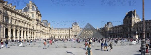 Sweeping view of the Louvre with the striking pyramid and many visitors on a sunny day, Paris