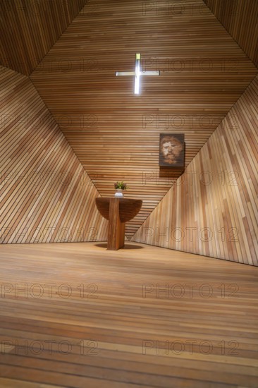 Modern interior of a wooden church with an altar table, flowers and a cross, minimalist design,