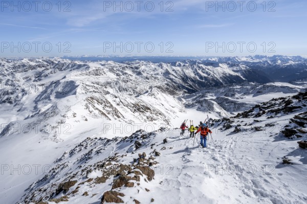 Ski tourer on foot, carrying skis on backpack, mountain panorama, snow-covered mountain landscape